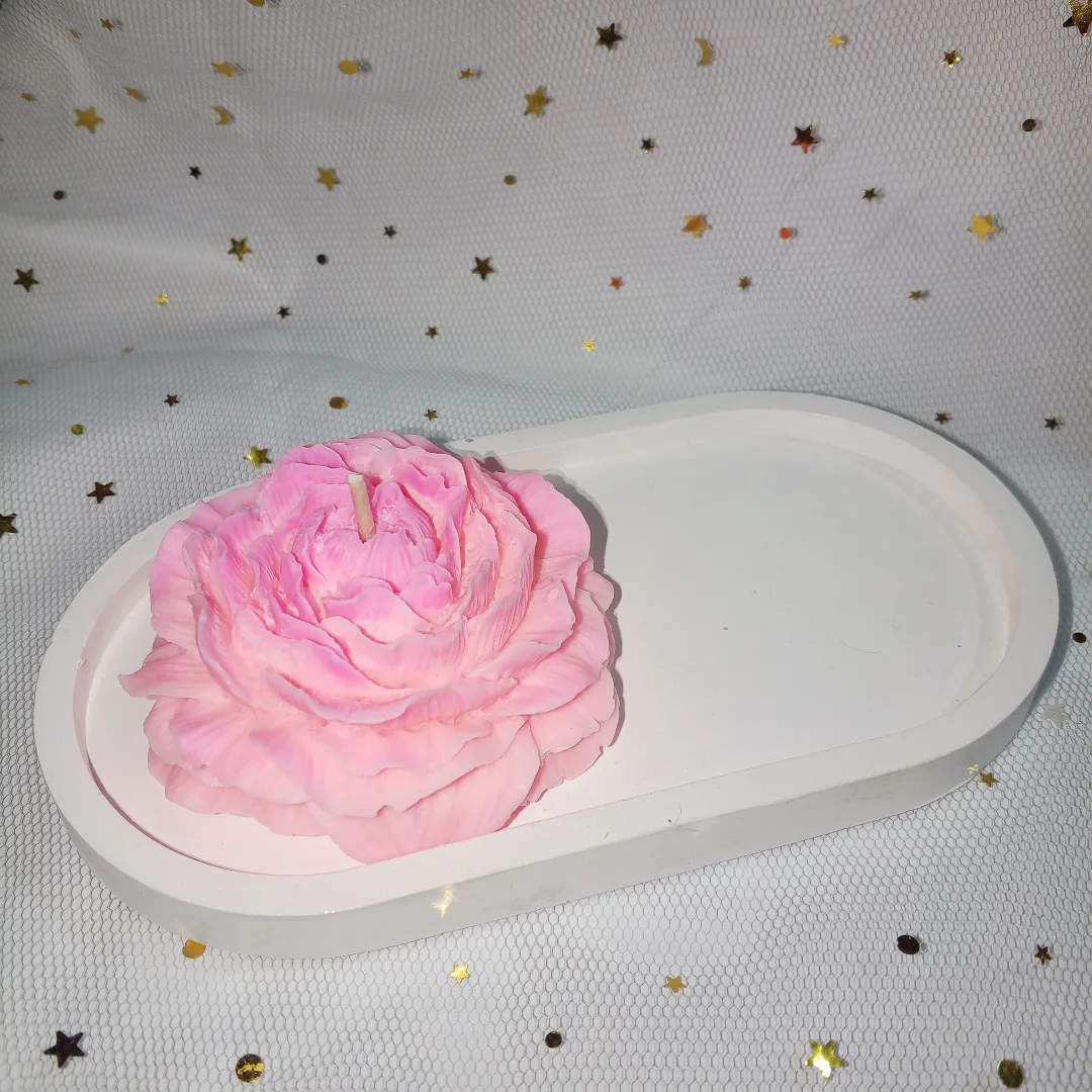 Vela de soja con forma de peonía rosa sobre bandeja de yeso